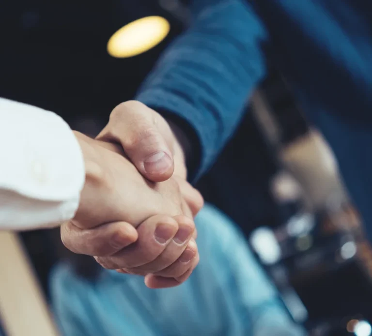 Poignées de main entre deux personnes dans un cadre professionnel.