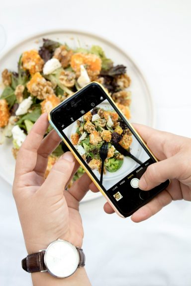 Une personne photographie une salade colorée avec des ingrédients variés.